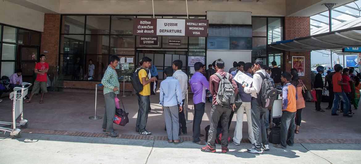 A group of Nepali migrant workers wait outside the International Terminal at Kathmandu airport, preparing to depart for work in the Middle East.