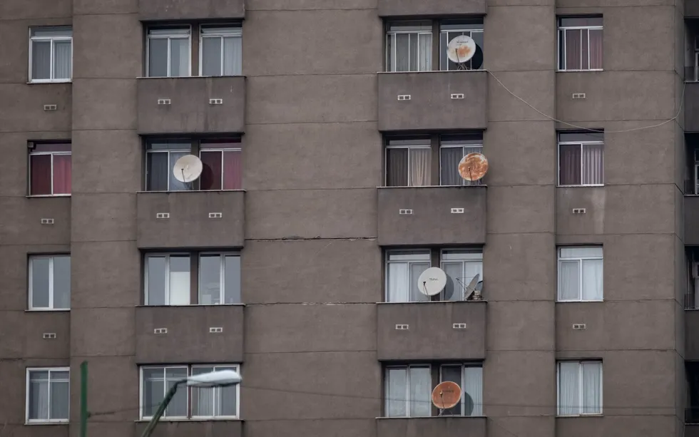 Photo of satellite dishes adorning the side of an apartment building.