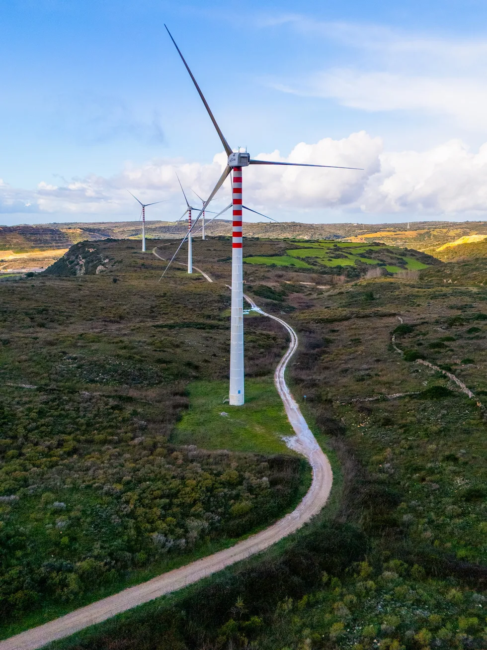 A bucolic landscape bisected by a road and row of wind turbines  