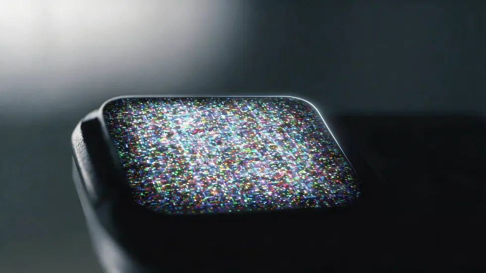 Close-up of a vision-based tactile sensor with 110,000 sensing units, resembling a smartwatch screen glowing with colorful digital static in the dark