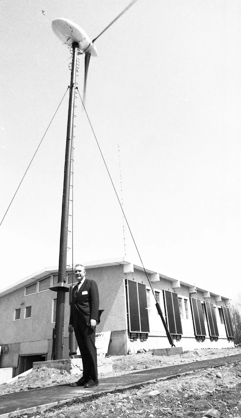 A man in a suit standing very straight outsider a modular home