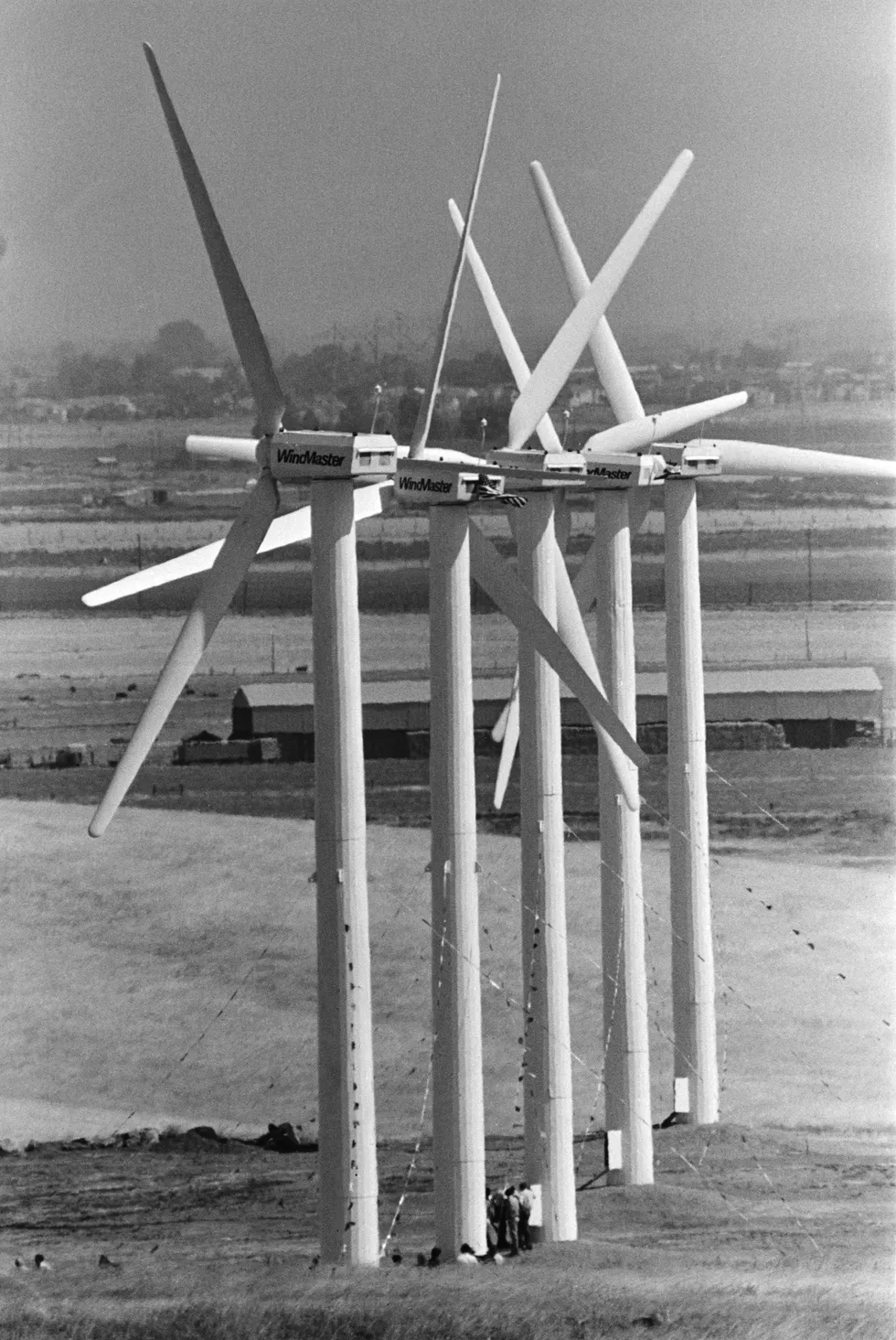 Five wind turbines mounted on freestanding poles on farmland