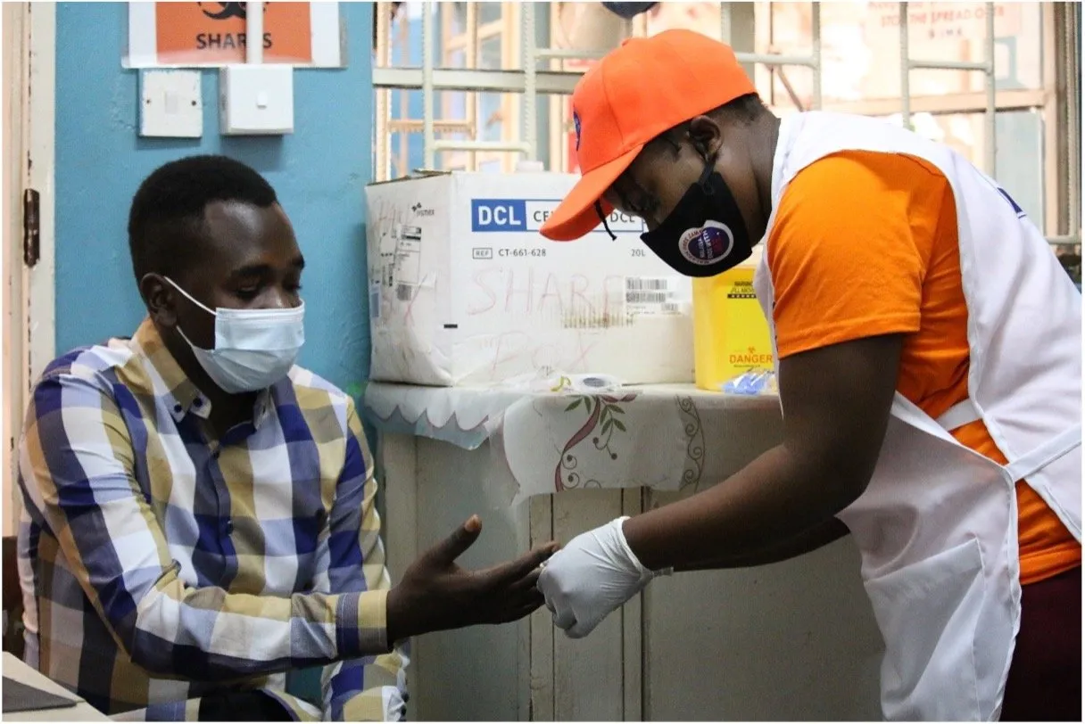 Community-health-worker-Bernadette-Chilufya-conducting-a-rapid-diagnostic-test-on-Christopher-a-patient-at-Nakambala-Clinic-in-Zambia.jp