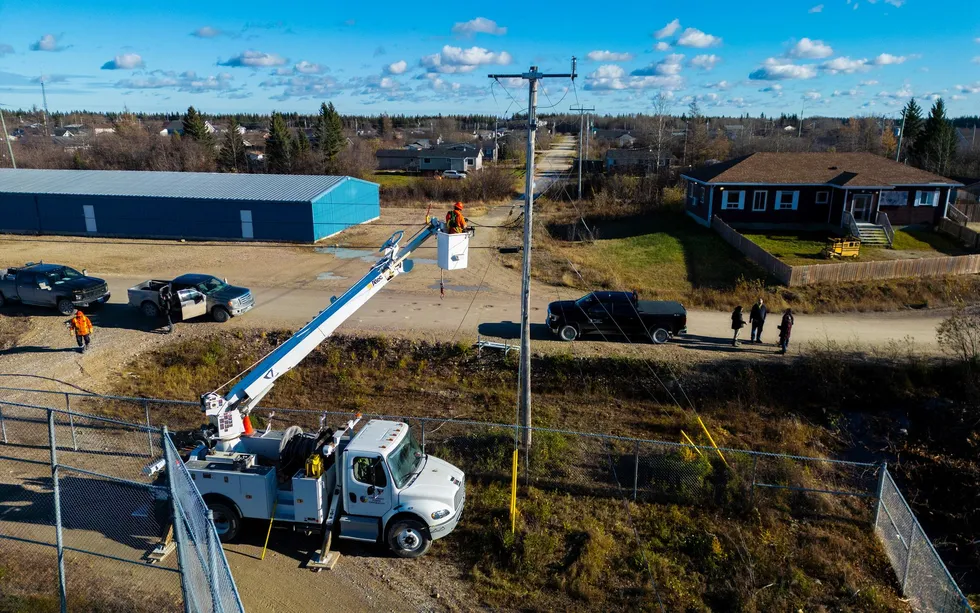 A photo shows a bucket truck with a man in the bucket approaching the top of a utility pole. 