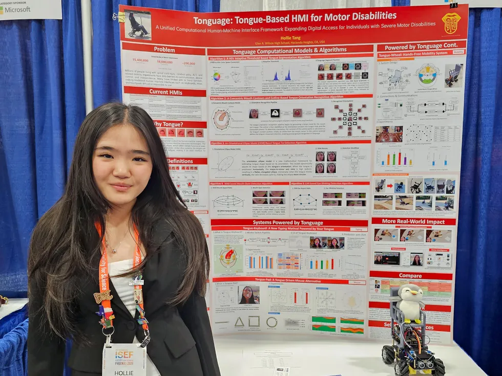 An Asian-American high school student standing in front of her research poster about tongue-based HMI for motor disabilities.