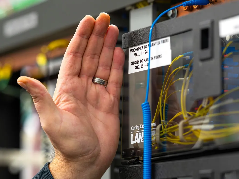 Hand adjusting fiber-optic cables in a labeled network equipment panel