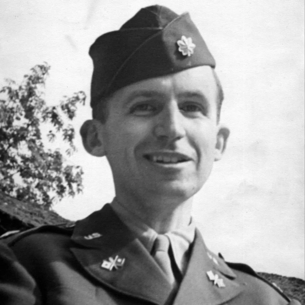 Smiling World War II-era U.S. Army officer in uniform and cap, shown in black and white.