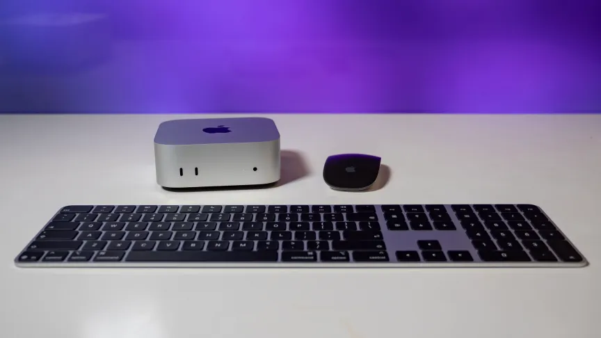 mac mini sitting next to a black magic mouse and behind a magic keyboard.