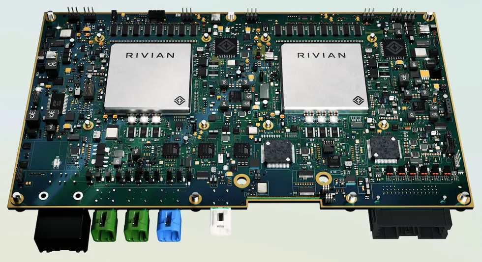 A densely packed green circuit board contains two silver-colored processors and scores of other chips and components.
