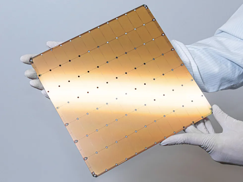 Gloved hands holding a large golden computer processor wafer