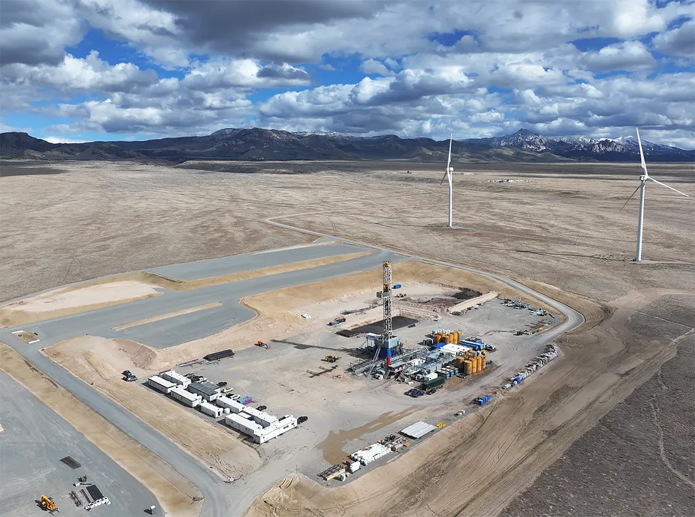 A tall, thin scaffold surrounded by tanks protrudes from the desert  